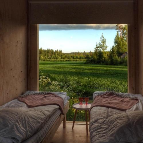 two beds in a room with a view of a field at KoloCabins - Hiitolanjoki 2 in Simpele
