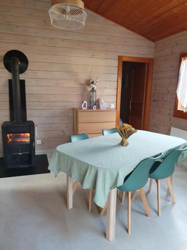 a dining room with a table and a stove at Le petit chalet de campagne in Richeling