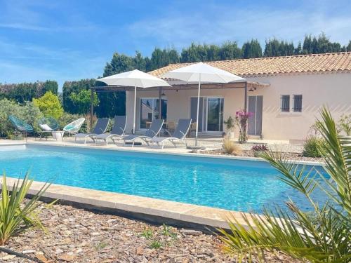 une maison avec une piscine avec chaises et parasols dans l'établissement Large modern house near St Rémy de Provence, à Graveson