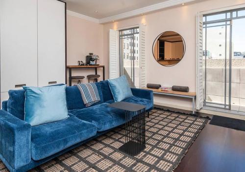 a blue couch in a living room with a mirror at Mandela Rhodes Place in Cape Town in Cape Town
