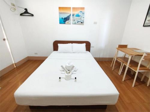 a white bed in a room with a table at Sulit Budget Hotel VMapa in Manila