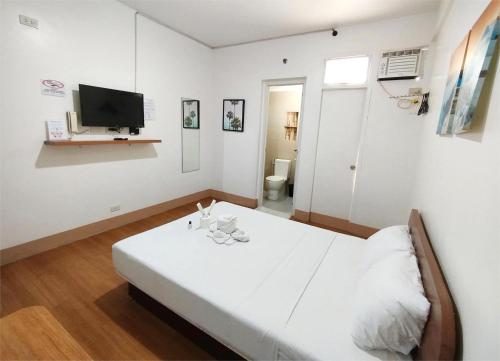 a white room with a bed and a television at Sulit Budget Hotel VMapa in Manila