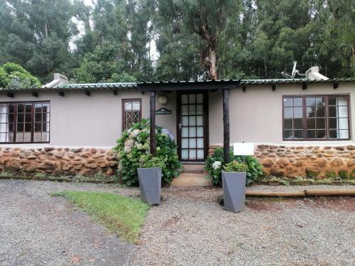 a white house with a stone wall at The Retreat Country Lodge in Romelcoh