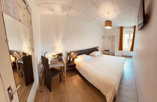 a bedroom with a bed and a desk and a table at Logis Hôtel restaurant des Voyageurs in Saint-Paulien