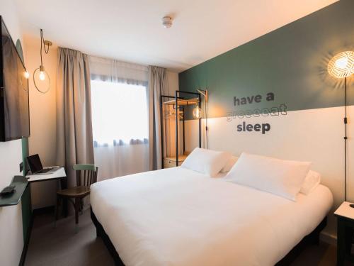 a bedroom with a white bed with ahave a sweet sleep sign on the wall at Greet Hotel Brest Aéroport in Guipavas