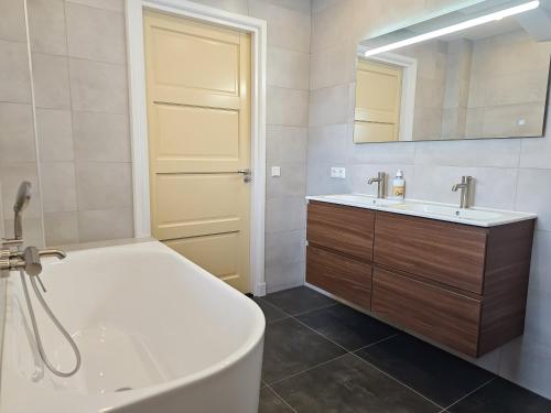 a bathroom with a tub and a sink and a mirror at Vakantiehuis Oostkapelle OK41 in Oostkapelle
