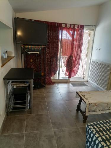 un salon avec une télévision et une grande fenêtre dans l'établissement Les grandes pouges, à Saint-Avit-Saint-Nazaire