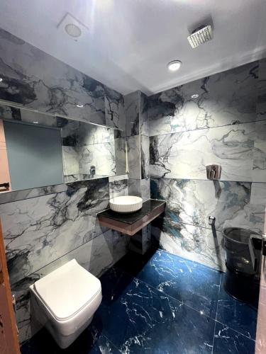 a bathroom with a white toilet and a sink at Hotel Cozzy Palace in Surat