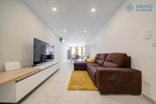 a living room with a couch and a flat screen tv at Modern Oasis Luxe with BigYard in San Ġwann
