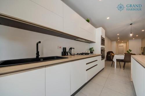 a kitchen with white cabinets and a sink at Modern Oasis Luxe with BigYard in San Ġwann