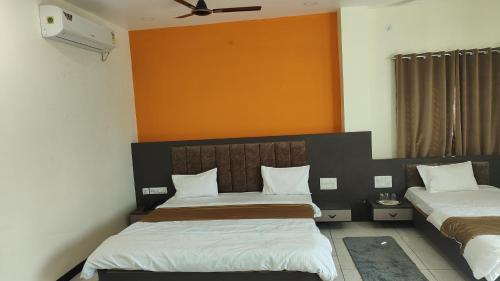 a bedroom with two beds and an orange wall at Yashomati Hotel in Maheshwar
