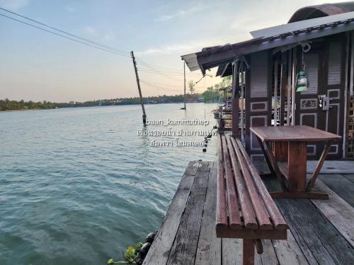 a wooden dock with a bench next to the water at p2 เรือนกระท่อมน้ำ เรือนรอยน้ำ บ้านกามเทพ อัมพวา โฮมสเตย์ in Amphawa