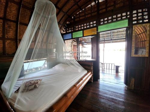a bed with a mosquito net in a room at p2 เรือนกระท่อมน้ำ เรือนรอยน้ำ บ้านกามเทพ อัมพวา โฮมสเตย์ in Amphawa