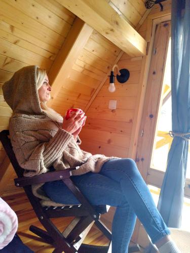 a woman sitting in a rocking chair holding a cup at Dedin Konak in Mokra Gora