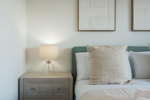 a bedroom with a bed with a lamp on a nightstand at Tai Porth Llechog Townhouse By Birch Stays in Amlwch