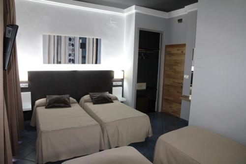 a hotel room with two beds and a hallway at Hostal Plaza Ruiz in Ceuta
