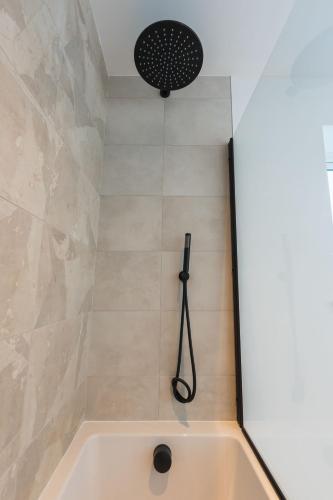 a bathroom with a shower with a bath tub at Tai Porth Llechog Townhouse By Birch Stays in Amlwch