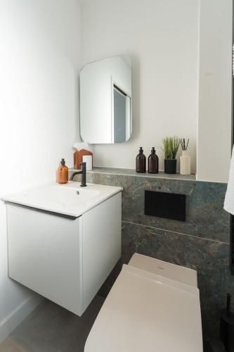 a white bathroom with a sink and a mirror at Tai Porth Llechog Townhouse By Birch Stays in Amlwch