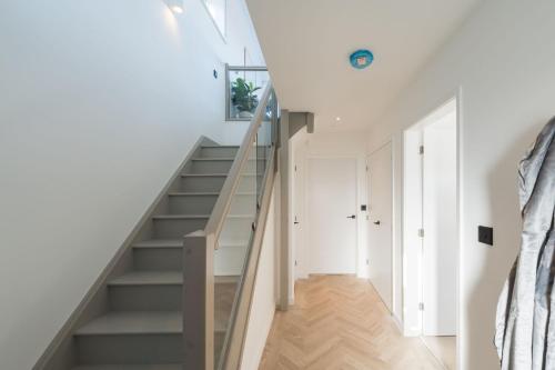 a staircase in a house with white walls and wood floors at Tai Porth Llechog Townhouse By Birch Stays in Amlwch
