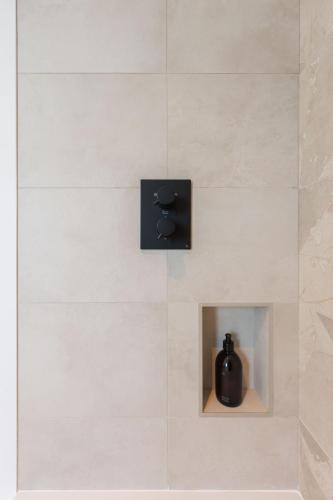 a black bottle in a niche in a bathroom wall at Tai Porth Llechog Townhouse By Birch Stays in Amlwch