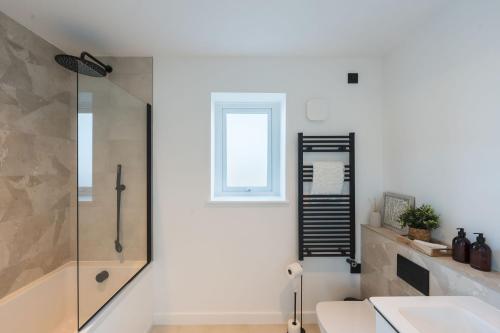 a bathroom with a shower and a toilet and a sink at Tai Porth Llechog Townhouse By Birch Stays in Amlwch