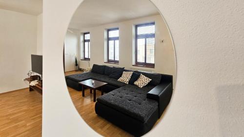 a living room with a black couch and a mirror at Apartmán na Krajzontě in Polná