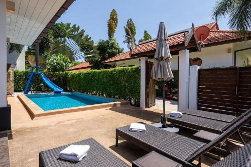 einen Pool mit Rutsche und Sonnenschirm in einem Hinterhof in der Unterkunft Family friendly villa in Phra Ae beach
