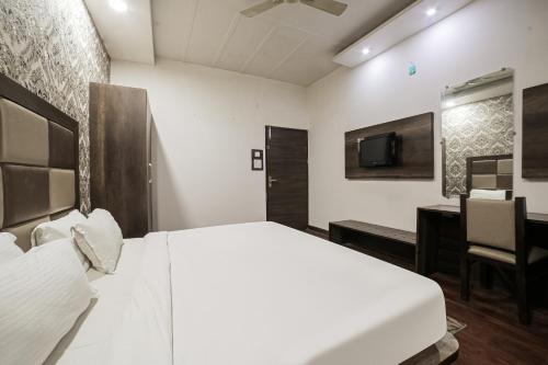 a bedroom with a white bed and a desk and a tv at Townhouse Hollywood Heights in Amritsar