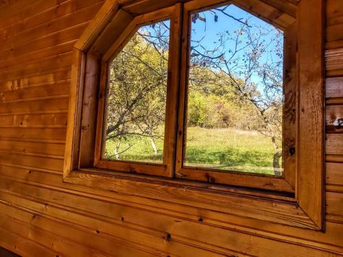 a window in a wooden cabin looking out at a field at Pensiunea Agroturistică Piscul Soarelui in Cîmpulung