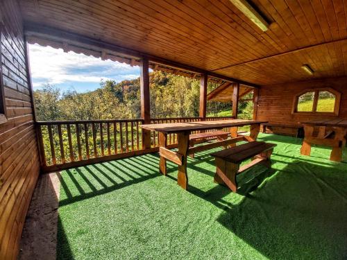 a screened in porch with a picnic table and benches at Pensiunea Agroturistică Piscul Soarelui in Cîmpulung