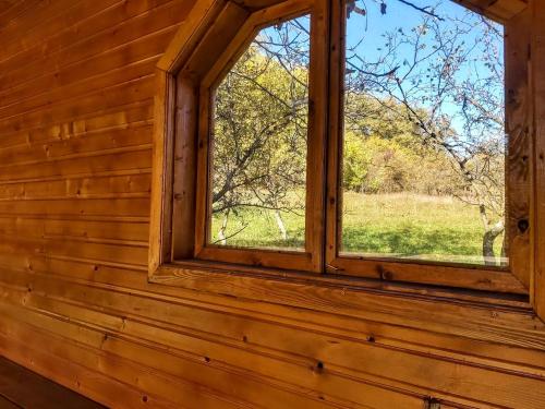 a window in a log cabin looking out at a field at Pensiunea Agroturistică Piscul Soarelui in Cîmpulung