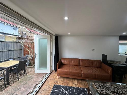 a living room with a couch and a table at Garden Studio Escape Open-Plan Comfort & Outdoor Space in London