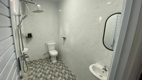 a white bathroom with a toilet and a sink at Asaan homestay in Ciburial