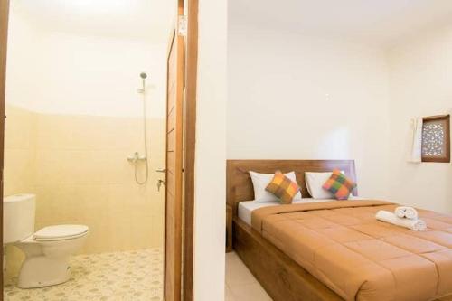 a bedroom with a bed and a bathroom with a toilet at Jempeng Homestay in Ubud