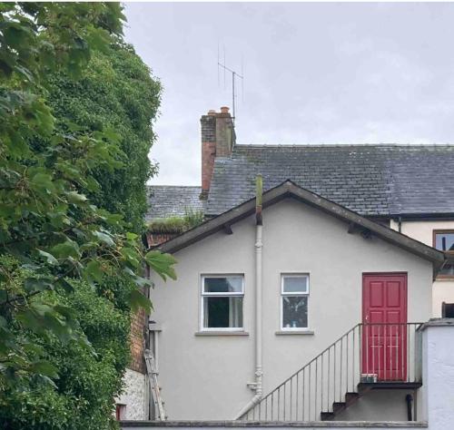 une maison blanche avec une porte rouge et des escaliers dans l'établissement Bridge street studios, à Cavan