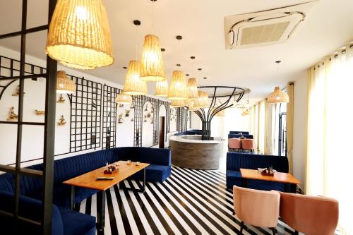 un restaurante con sofás azules, mesas y lámparas de araña en Hari Mahal Resort, en Behror