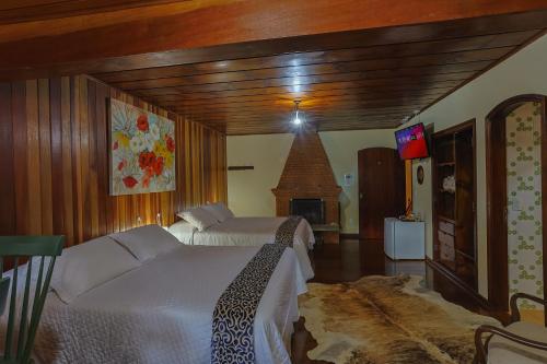 a bedroom with two beds and a fireplace at Pousada Cantos e Contos in Monte Verde