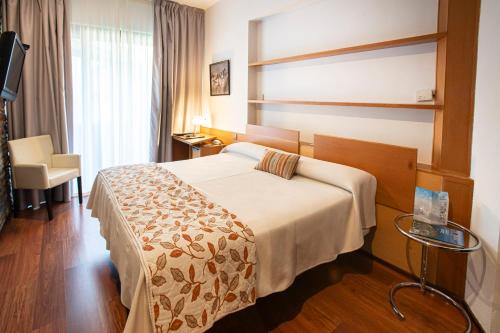 una habitación de hotel con una cama y una silla en Hotel Parque de Monfragüe, en Torrejón el Rubio