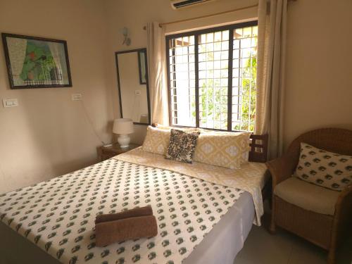 a bedroom with a bed with a window and a chair at Bella Boutique Homestay in Alleppey