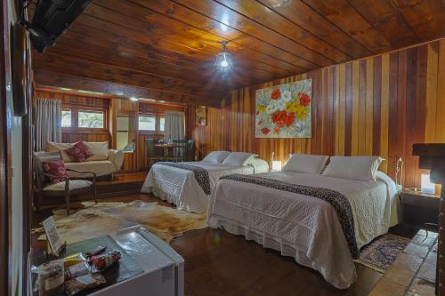 a bedroom with two beds in a room with wooden walls at Pousada Cantos e Contos in Monte Verde