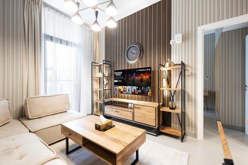 1BR Apartment With Balcony - 9 Mins to Sharjah Airport - Balcony Breeze في الشارقة: غرفة معيشة مع أريكة وتلفزيون