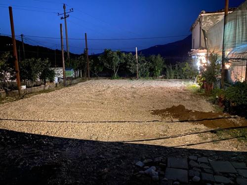a gravel driveway with a fence and a building at Parking& Campsite Bakiaj in Tepelenë