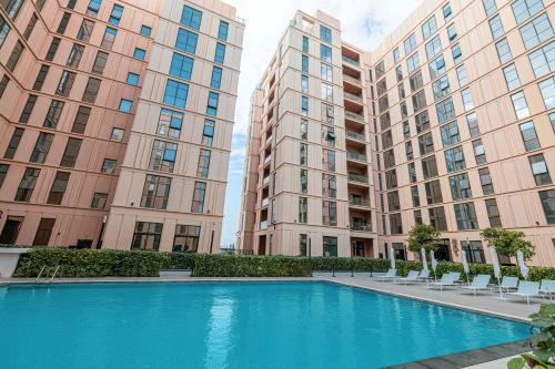 a swimming pool in the middle of two tall buildings at 1BR Apartment With Balcony - 9 Mins to Sharjah Airport - Balcony Breeze in Sharjah
