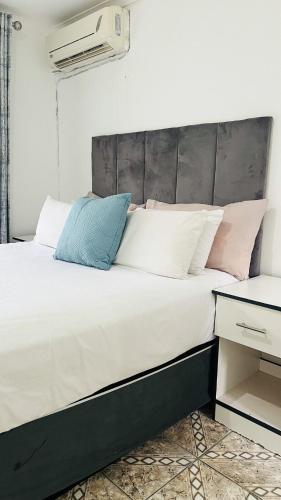 a bedroom with a large white bed with pink and blue pillows at Sibusi Guesthouse in Richards Bay