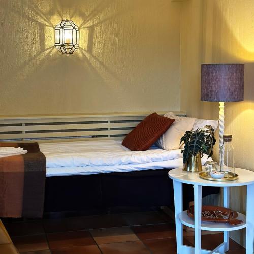 a bed in a room with a lamp and a table at Villa Beddingestrand in Beddinge Strand