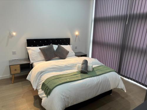 Un dormitorio con una cama grande con una toalla encima. en Elegant Apartment in Central Milton Keynes, en Milton Keynes