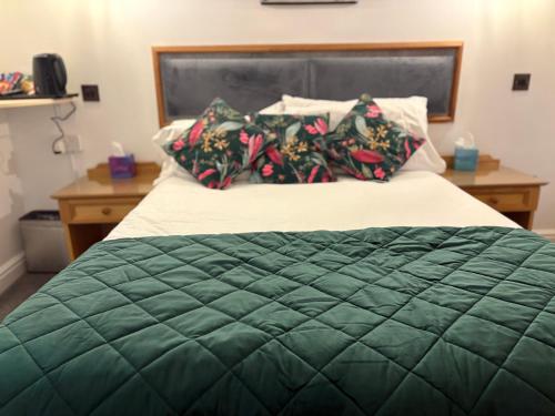 a bed with a green comforter and two pillows at Masons Arms in Skipton