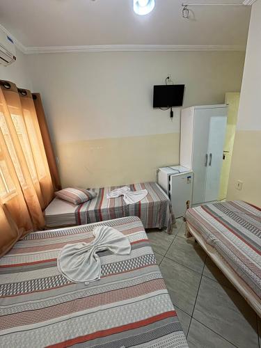 a hotel room with two beds and a television at Hotel Luz Do Sol in Aparecida