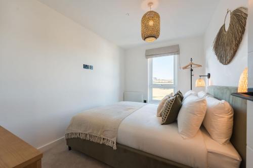 a bedroom with a bed with pillows and a window at Gwel Y Mor Penthouse By Birch Stays New Home in Amlwch