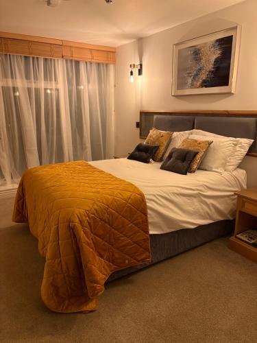 a bedroom with a large bed with an orange blanket at Masons Arms in Skipton